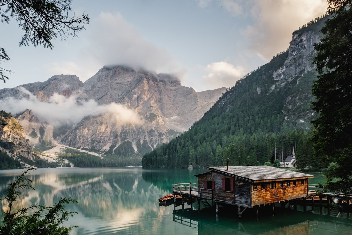 A wooden cabin deck looking out over a still lake at first light